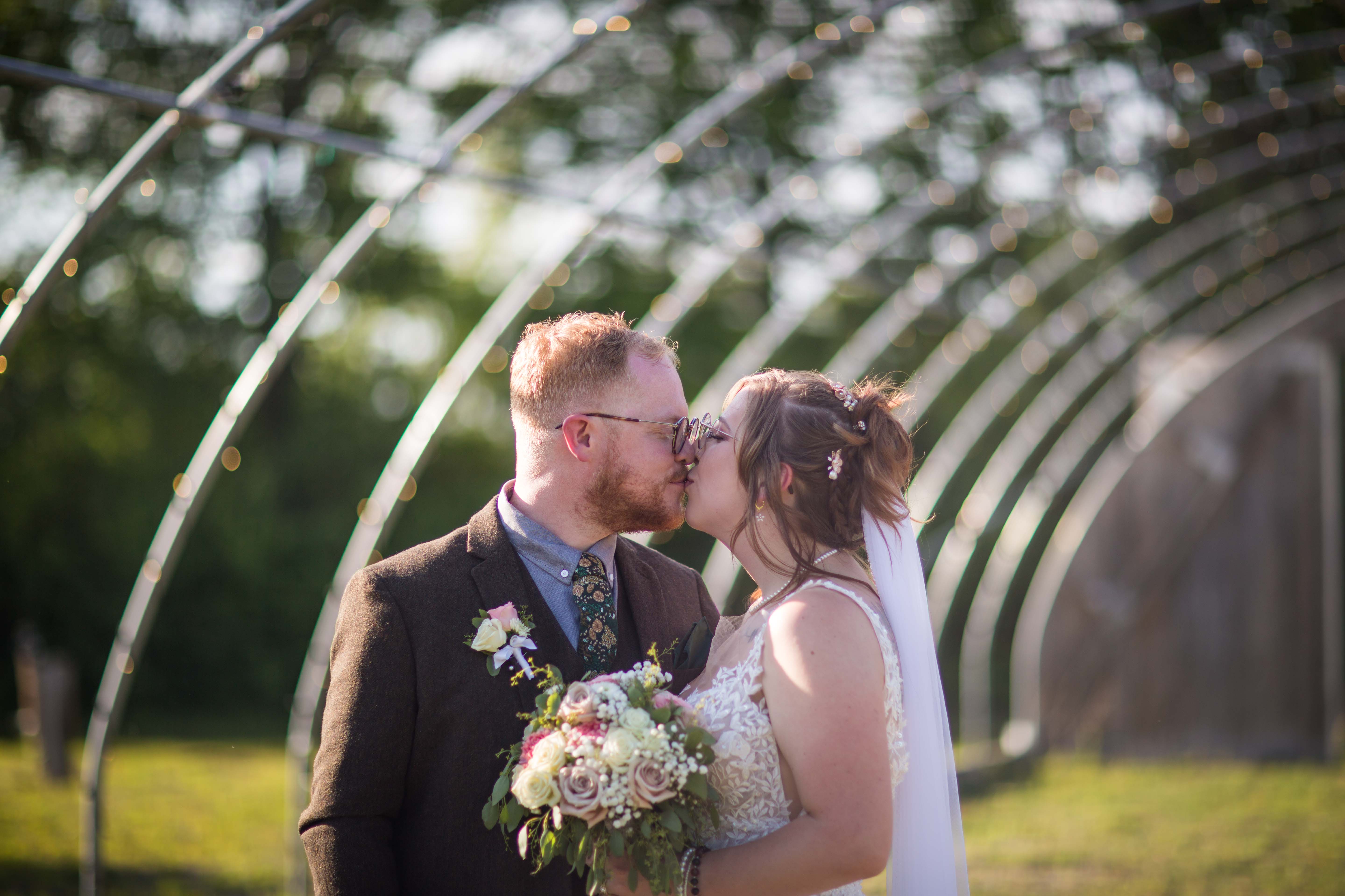 Hillary and Jake sharing a kiss outdoors at Gardens of Woodstock